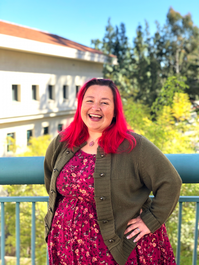 A woman with bright red hair laughing outside