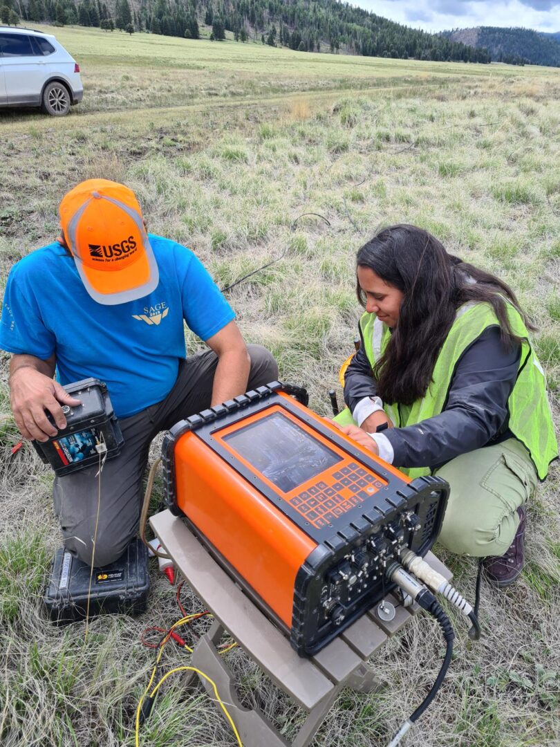 Vanessa and a USGS team member collect data using an orange machine