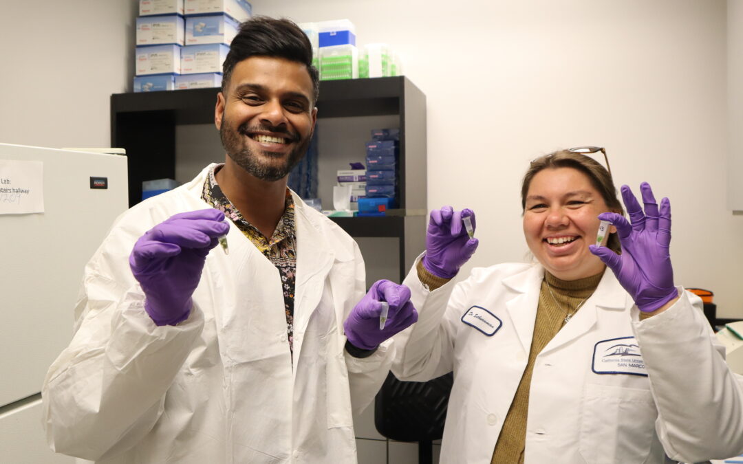 Arun Sethuraman and Alex Adame smile while holding pipette samples of hops