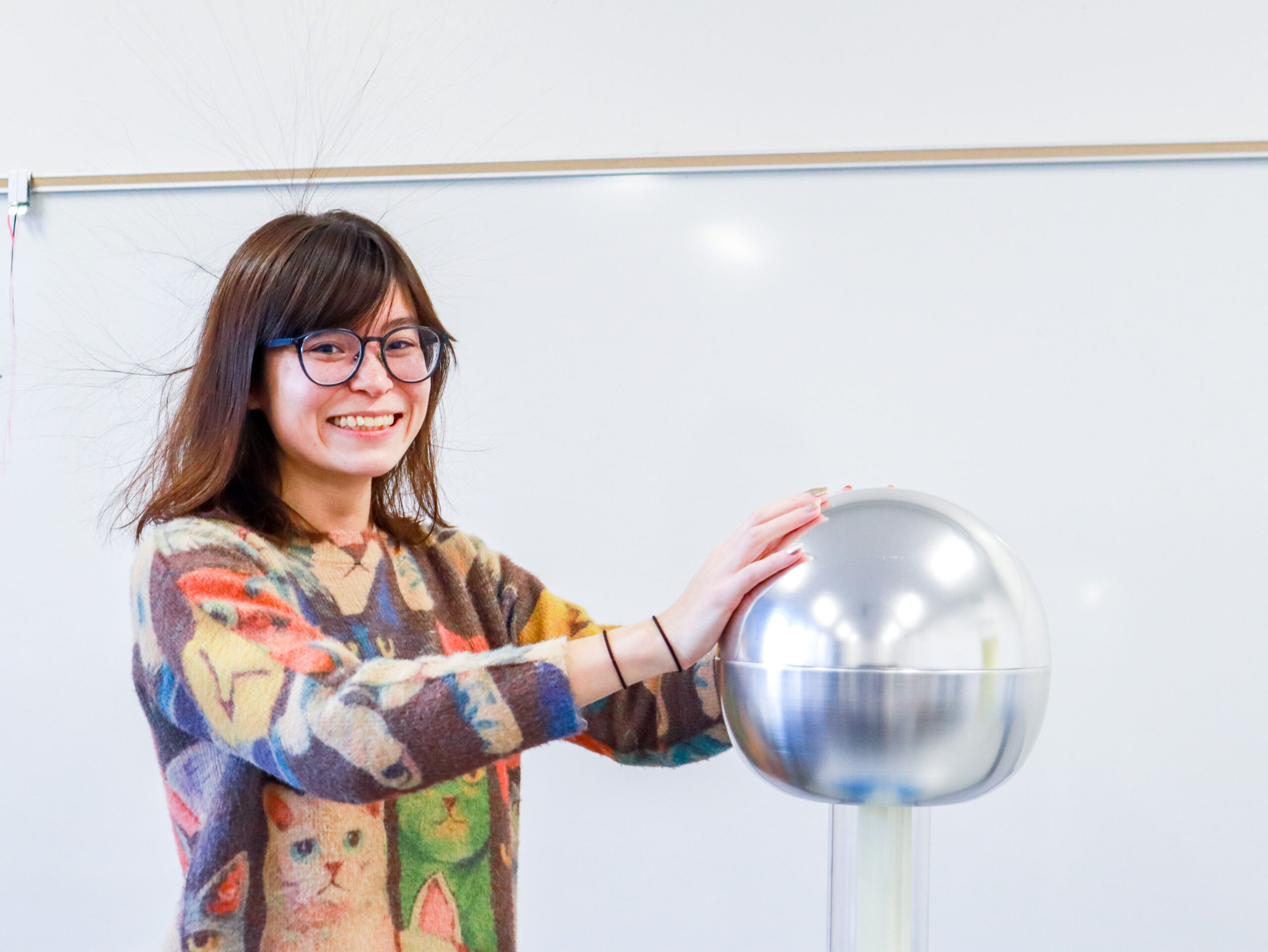 Ngara Bird's hair stands on-end while she touches a machine that generates static electricity