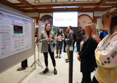 Student explains their chemistry poster to onlookers