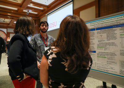 Student explains their chemistry research to President De La Torre and Vice President Madanat