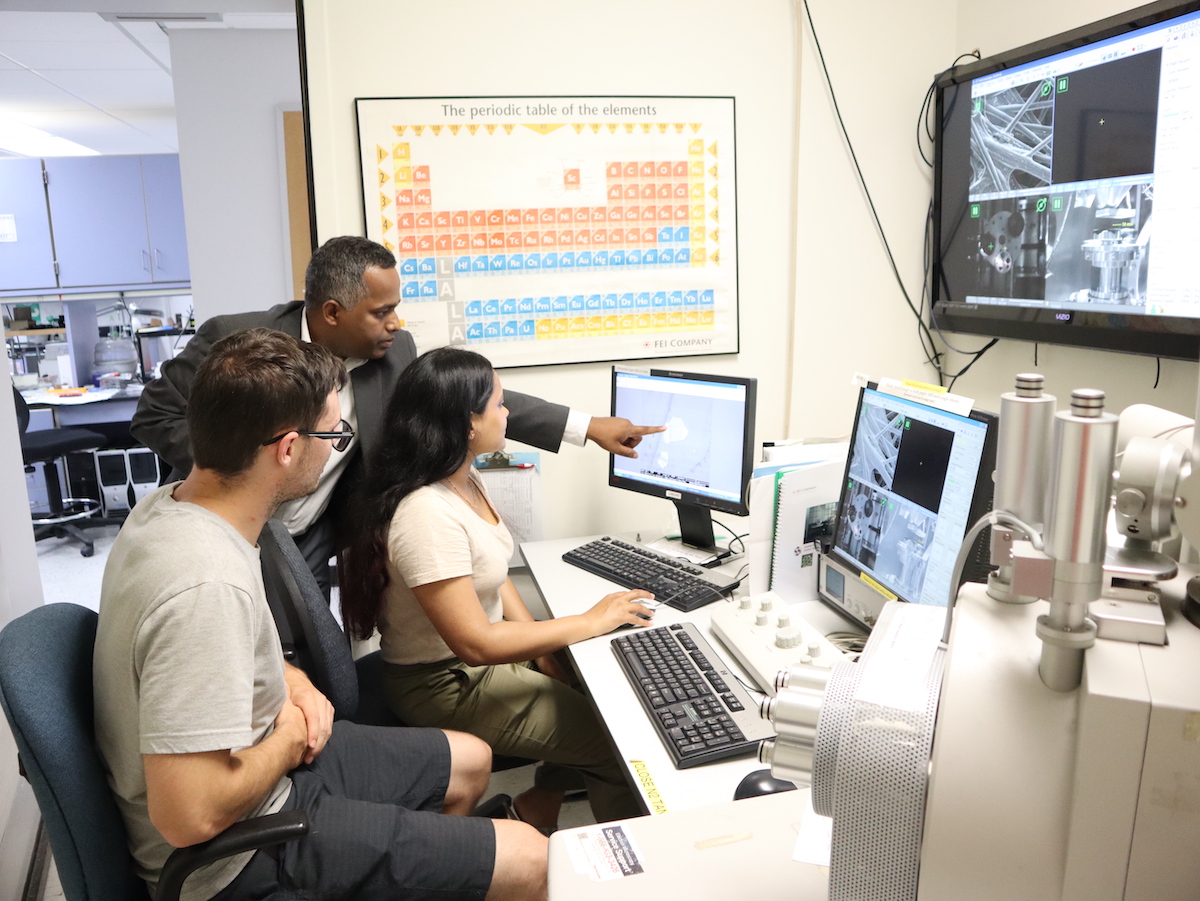 Sanjay Behura (middle) in the Electron Microscopy Facility pointing to a crystal of two-dimensional material exposed to electron beam irradiation.