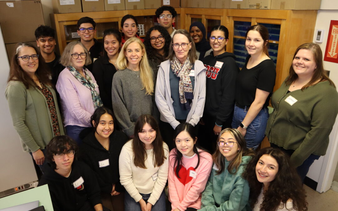 The four principal investigators who manage the Biotech Scholars program pose for a photo in the lab with their cohort of fourteen undergraduate students