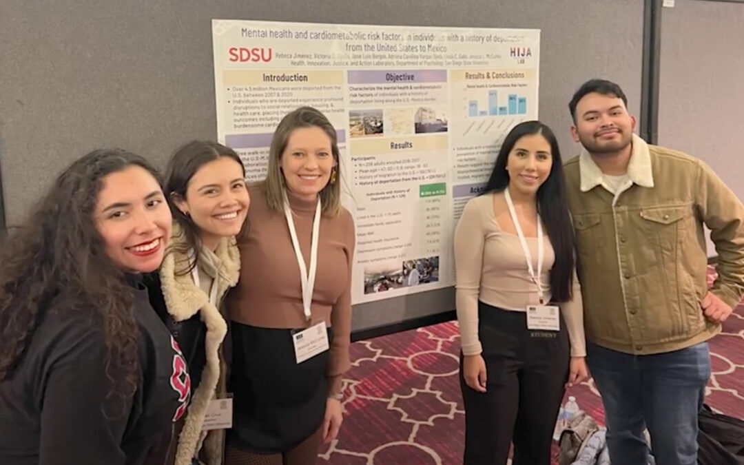 SDSU researchers smile in front of a research poster
